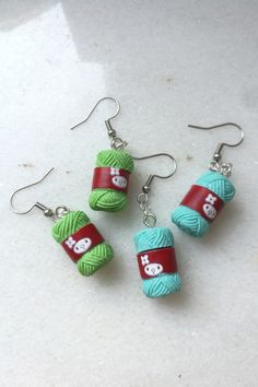 three balls of yarn are hanging from earrings