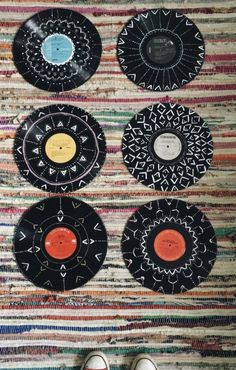 four black and white plates sitting on top of a colorful rug next to two pairs of shoes