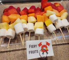 fruit skewers are arranged on sticks with a sign that says fiery fruits next to them