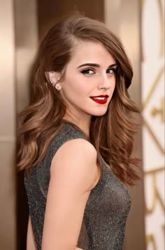 a woman with long hair and red lipstick posing for the camera at an oscars event