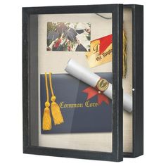 a graduation cap, diploma and other items are in a shadow box that is decorated with gold tassels