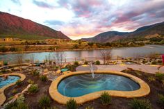 an outdoor hot tub next to a lake with mountains in the background