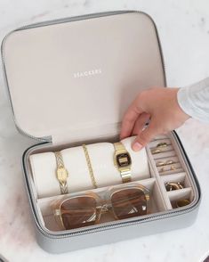 a person is holding some glasses in a case with other items inside it on a marble table