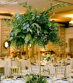 a tall centerpiece with greenery sits on top of a table