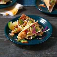 two plates with tacos on them sitting on a table next to other food items