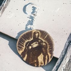 a wooden keychain with an image of a man holding a shield on it