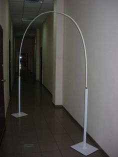 an empty hallway with two white poles and a clock on the wall behind it, along with tiled flooring