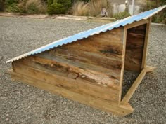 a dog house made out of wood with a blue roof and shingles on top