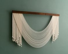 a wall hanging made out of macrame and wood with white strings attached to it