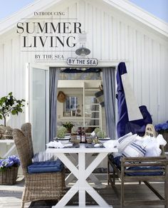 a white house with blue and white decor on the front door, sitting outside in wicker chairs