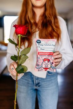 a woman is holding a rose and a packet of sweet hearty treats for valentine's day