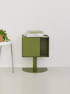 a green cabinet sitting next to a white table with a potted plant on top