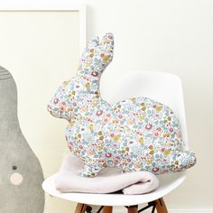 a stuffed rabbit sitting on top of a white chair next to a gray elephant statue