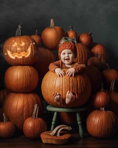 a baby sitting in a chair surrounded by pumpkins