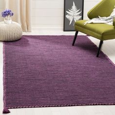 a purple rug in a living room with a green chair and white wall behind it