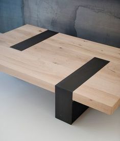 a wooden table with two black strips on it's sides and a gray wall behind it