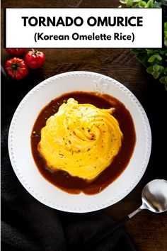 a white plate topped with an omelet covered in gravy next to a spoon