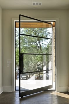 an open glass door leading to a patio with trees in the backgroung