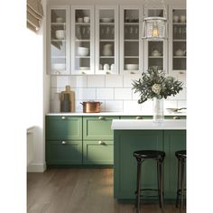 a kitchen with green cabinets and white counter tops