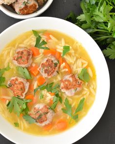 two bowls of soup with meatballs, carrots and parsley on the side