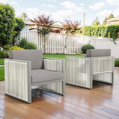 two gray chairs sitting on top of a hard wood floor next to a white fence