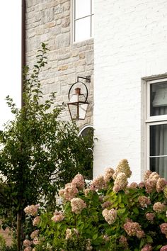 a white brick building with flowers in the foreground