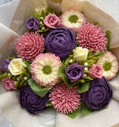 a bouquet of purple and white flowers sitting on top of a piece of paper with green leaves