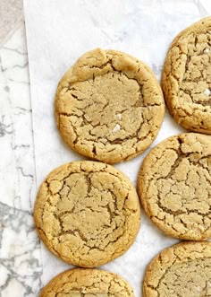 a close up of many cookies on a white tablecloth with one cookie in the middle