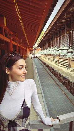 a woman standing next to a rail near a train station with lots of empty seats