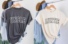 two t - shirts hanging on clothes racks with the words uncle and aunte printed on them