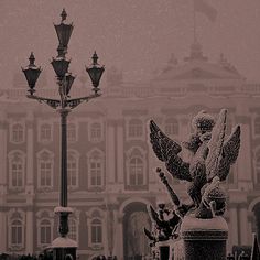 an angel statue sitting on top of a stone pillar in front of a large building