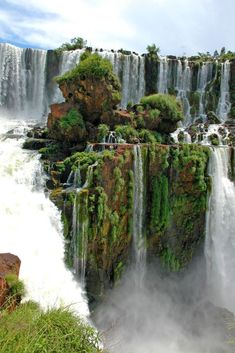 the waterfall is surrounded by lush vegetation and water cascading down it's sides