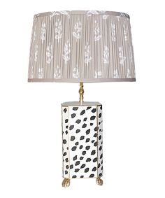 a table lamp with a white and black design on the base, next to a beige lampshade