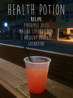 a pink drink sitting on top of a wooden table next to a window sill