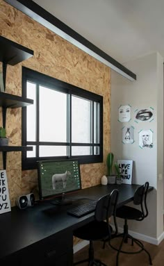 a desk with a computer on top of it in front of a wooden paneled wall