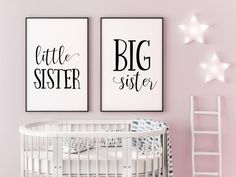 two black and white prints on the wall above a crib in a pink nursery