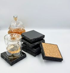 four coasters with different types of alcohol in them on a white surface, next to a bottle of liquor