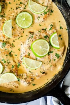 a skillet filled with chicken covered in sauce and garnished with limes