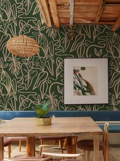 a dining room with green wallpaper and wooden chairs