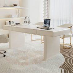 a white desk with a laptop on it in front of a chair and bookshelf