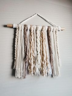 there is a wall hanging made out of yarn and some wood sticks on the wall