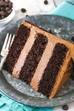 a piece of chocolate cake on a plate with a fork and coffee beans in the background