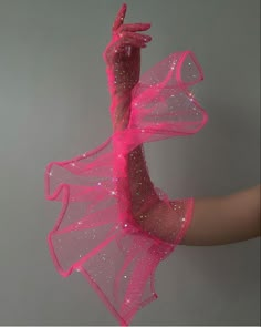 a woman's arm with pink sequins on it, holding onto a string