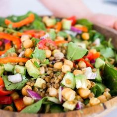 a salad in a wooden bowl with lettuce, carrots and chickpeas