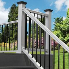 a white railing with black handrails next to some trees