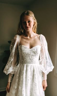 a woman wearing a white dress standing in front of a window