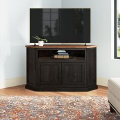 a flat screen tv sitting on top of a wooden cabinet in front of a window