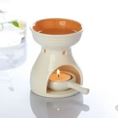 a small white candle holder sitting on top of a table next to a glass filled with water