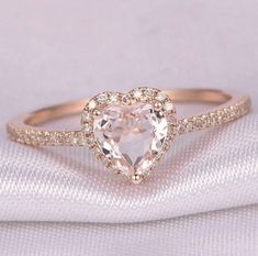 an engagement ring with a heart shaped diamond in the center on top of a white cloth