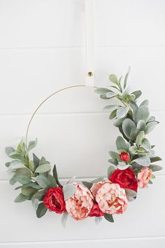 a wreath with flowers and greenery hanging on the wall